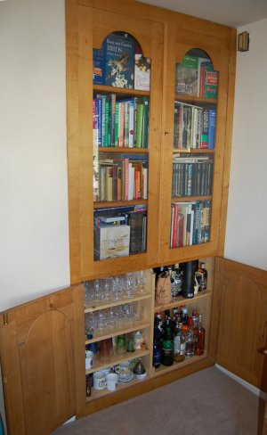 Closed glass dors to the bookshelves, drinks cabinet below.